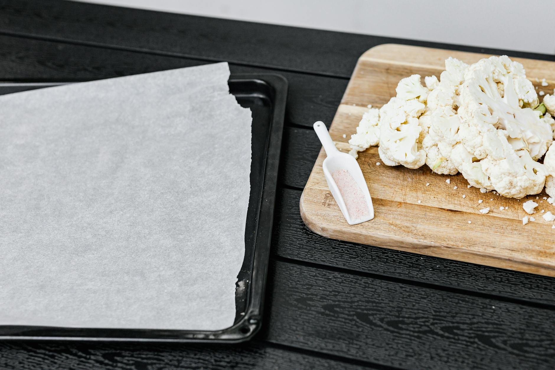 Kalafior na desce obok blachy do pieczenia, przygotowanie kotletów