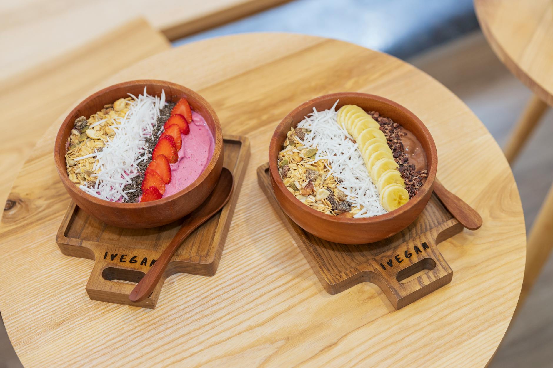 Kolorowe wegańskie miski smoothie z owocami i granolą na drewnianym stole