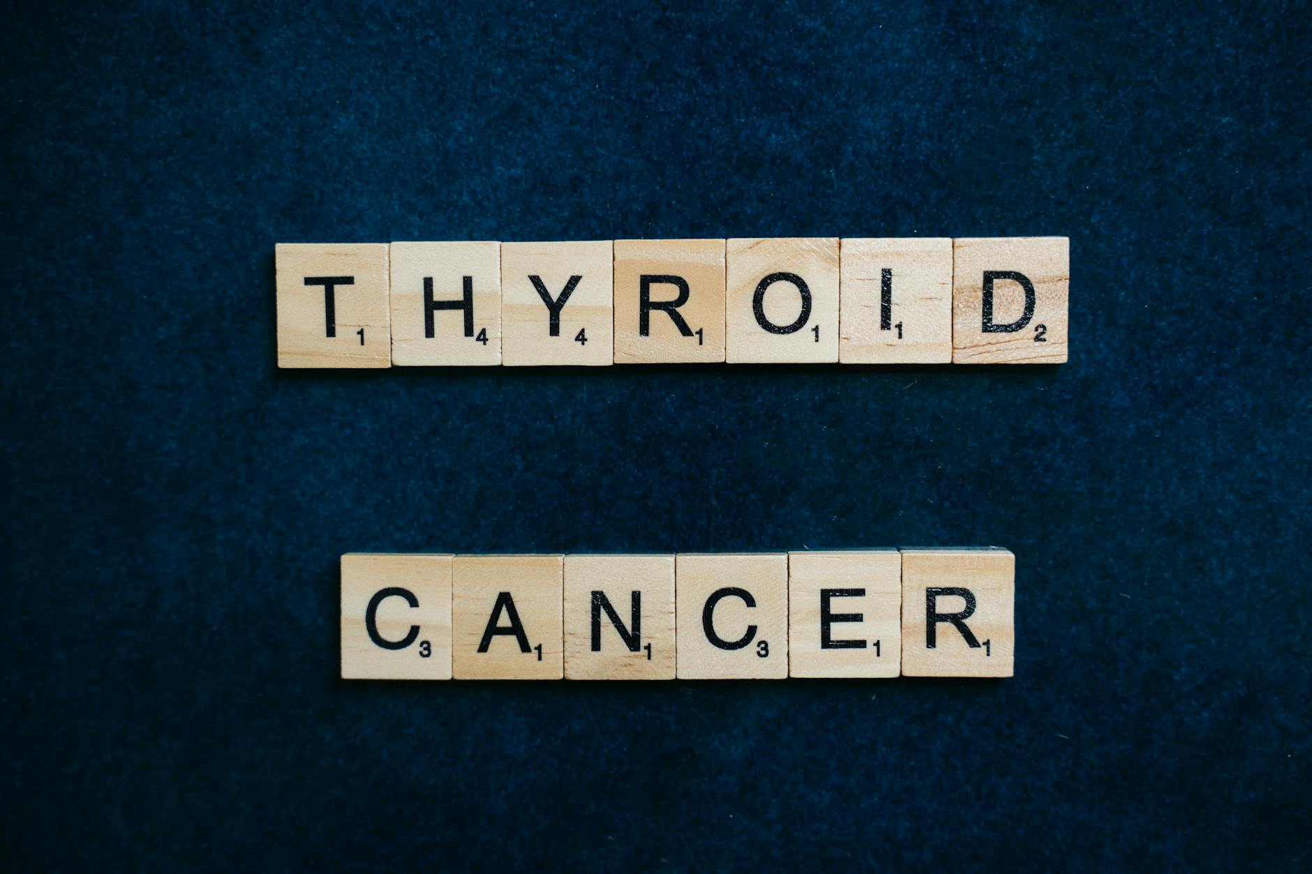 Napis Thyroid Cancer z klocków scrabble na granatowym tle