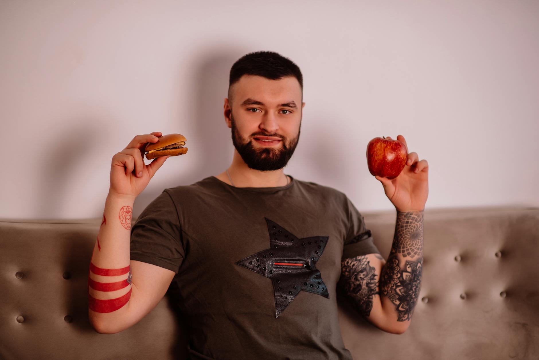 Brodaty mężczyzna zastanawia się między jabłkiem a burgerem