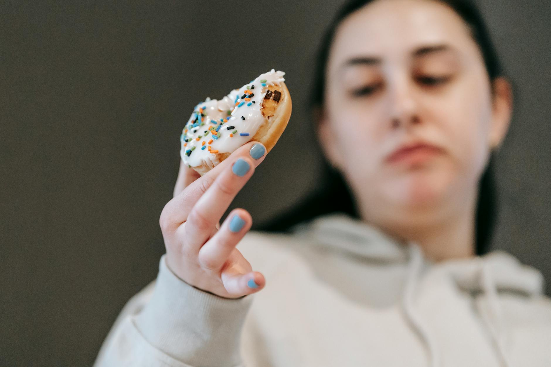 Kobieta obojętnie jedząca lukrowanego pączka przy insulinooporności
