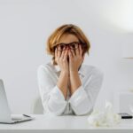 Zestresowana kobieta przy biurku z laptopem i chusteczkami