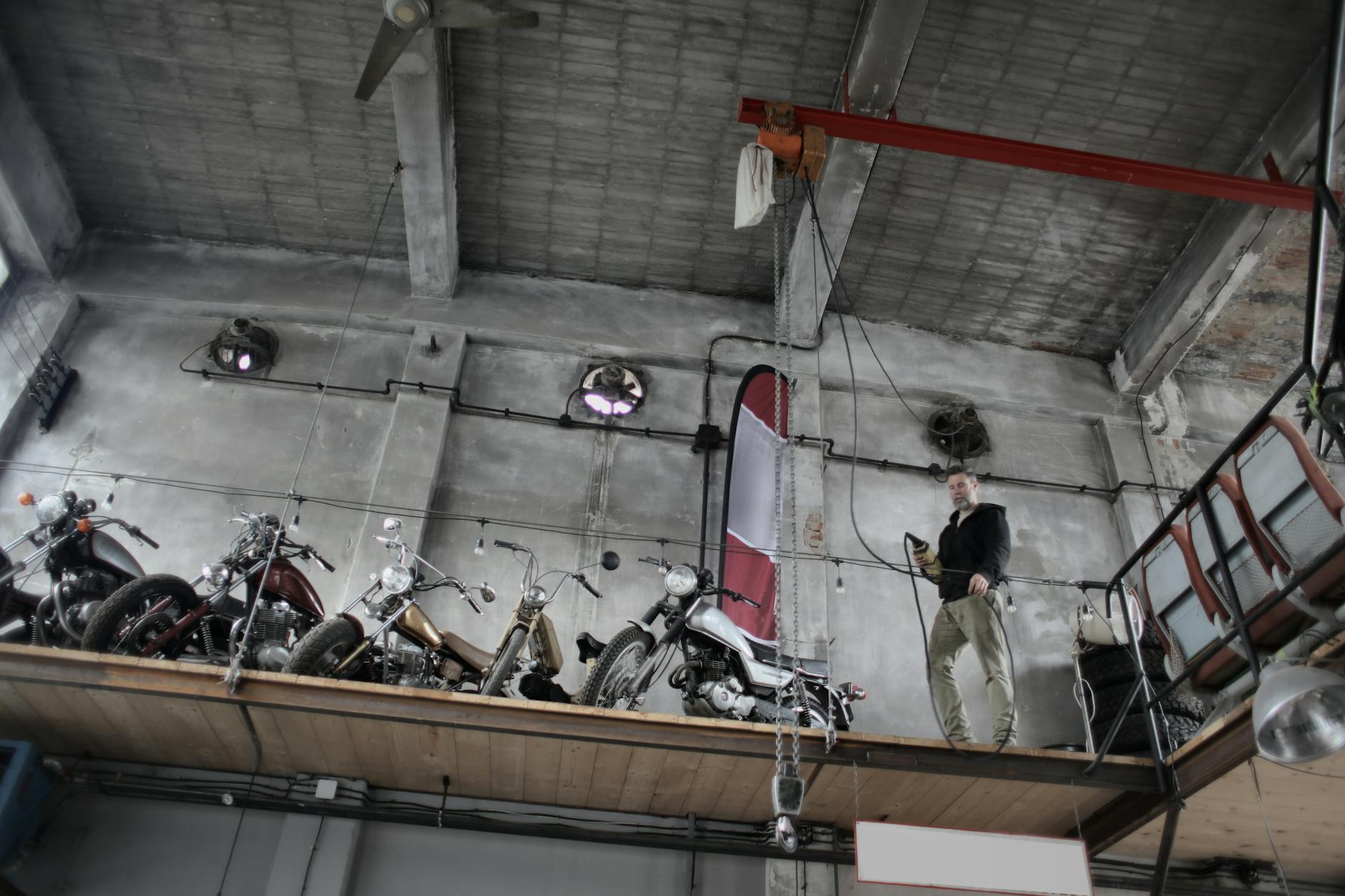 Mechanik w garażu obsługuje podnośnik z motocyklem na platformie