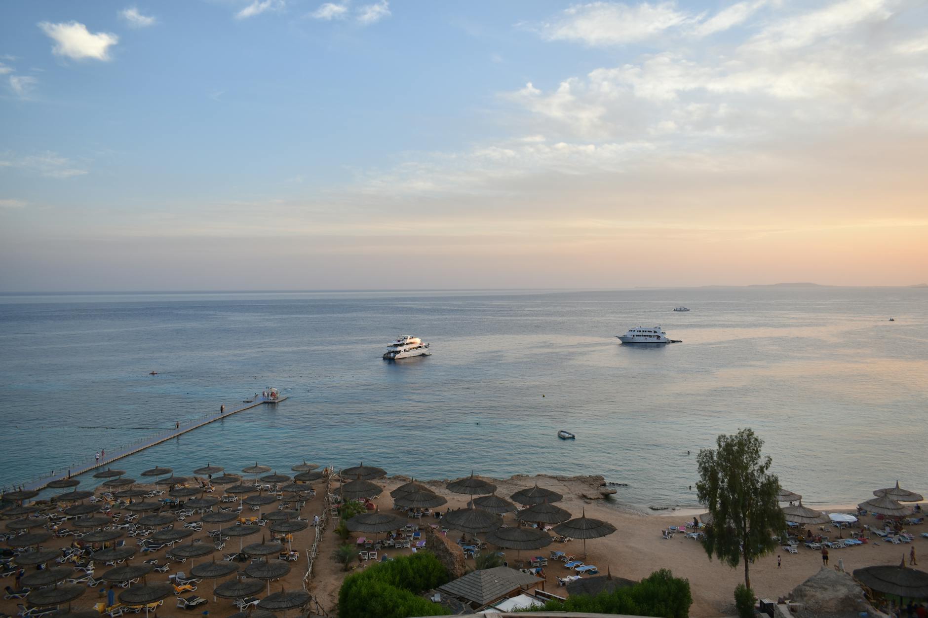 Plaża w Sharm El Sheikh o zachodzie słońca z łodziami i parasolami