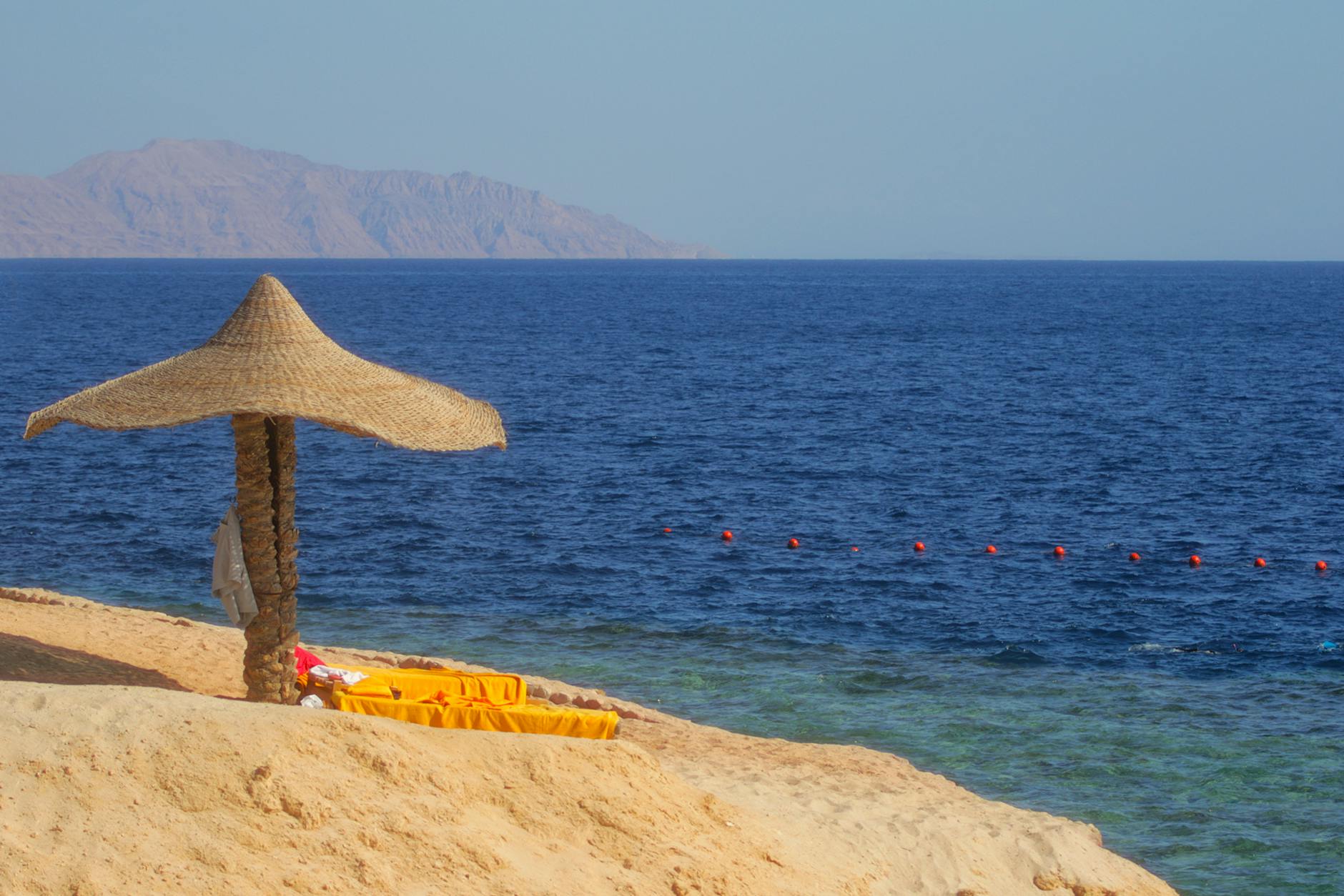 Pusta plaża w Sharm El Sheikh z parasolem i turkusowym morzem Pusta plaża w Sharm El Sheikh z parasolem i turkusowym morzem