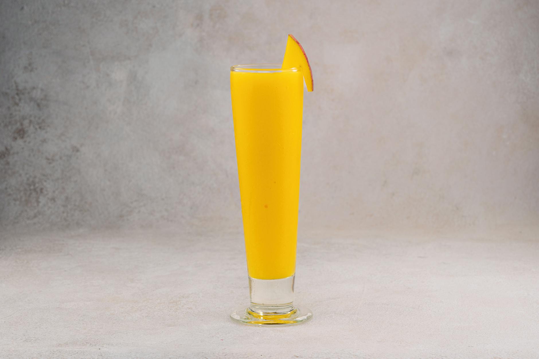 Szklanka jasnego koktajlu z mango z plasterkiem na brzegu