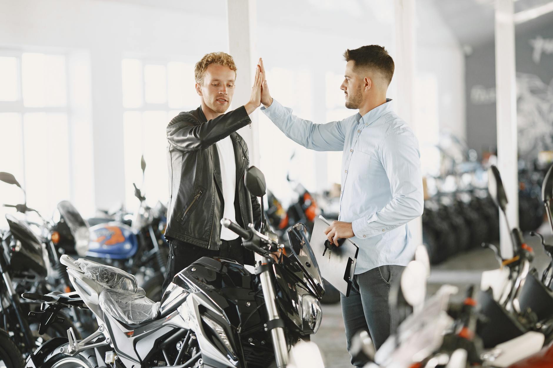 Jak bezpiecznie kupić używany motocykl sportowy online i sprawdzić jego historię przed zakupem Dwaj mężczyźni przybijają piątkę przy zakupie motocykla w salonie
