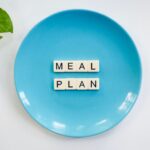Weekendowy plan naprawczy przy insulinooporności: posiłki, ruch i sen, które stabilizują glukozę w 48 godzin Napis meal plan z klocków na niebieskim talerzu z zielonymi liśćmi